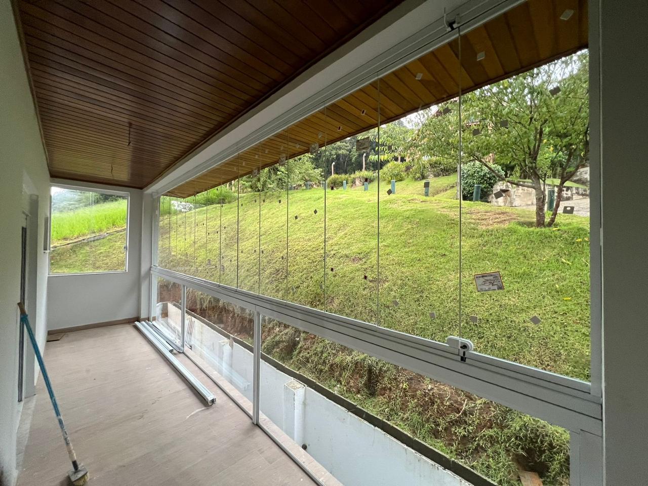 Varanda envidraçada com vidros de correr e vista para jardim